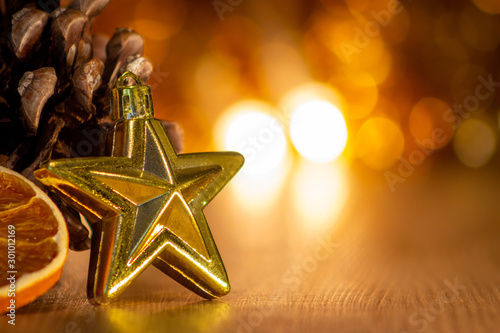 stella dorata di natale con fetta d'arancia su fondo legno e luci con effetto bokeh