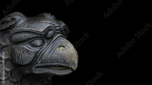 Banner of ancient statue of medieval griffin, a hybrid of lion and bird, covered with moss isolated at black background with paste space, closeup, details