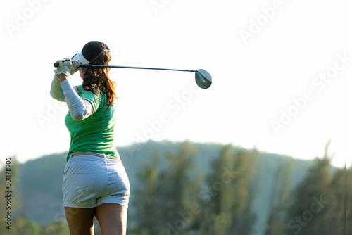 Healthy Sport. Asian Sporty woman golfer player doing golf swing tee off on the green, people presumably does exercise. Healthy Lifestyle Concept.