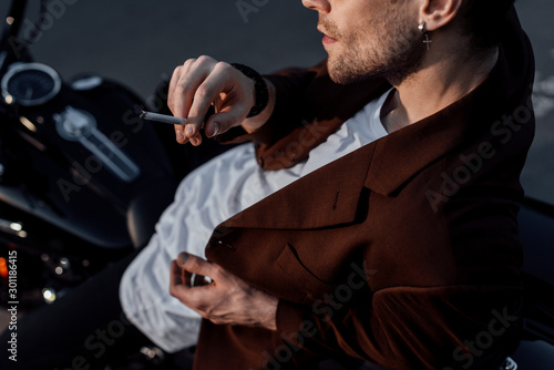cropped view of man smoking cigarette while sitting on motorcycle