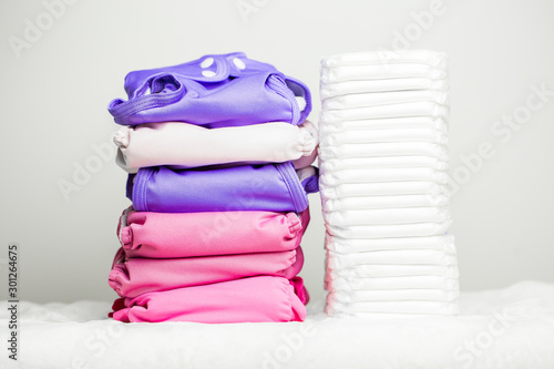 Stacks of eco friendly washable textile diapers and modern disposable diapers together.