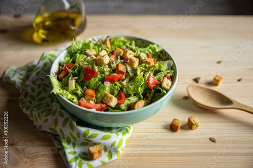 salad with tomatoes, avocados, croutons and wooden spoon
