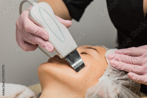 close-up. Ultrasonic face cleaning. Modern equipment. Beautician does cosmetic procedure on woman face.