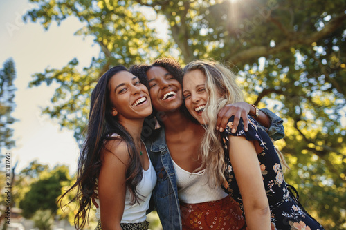 Portrait of a happy multiethnic group of smiling female friends - women laughing and having fun in the park on a sunny day