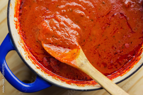 Authentic marinara sauce shown with wooden spoon in a cast iron dutch oven. 