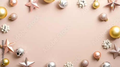 Christmas frame. Top view elegant Xmas decorations, golden and silver balls, pink stars on pastel ivory background. Glamour greeting card template, Christmas party invitation with copy space.