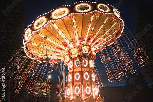 Illuminated swing chain carousel in amusement park at the night