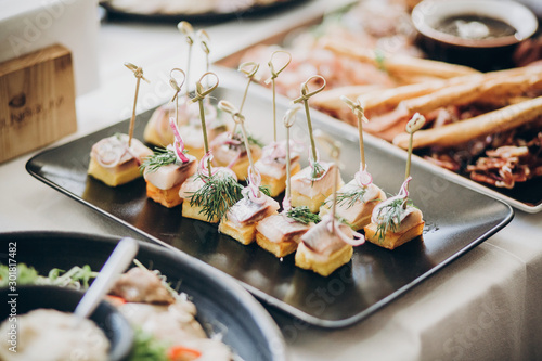 Delicious food table at wedding reception. Fish finger appetizers with onion on table at wedding or christmas feast. Luxury catering concept