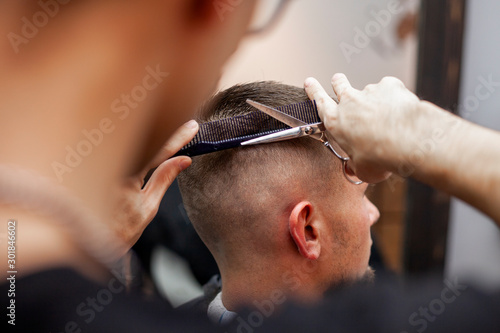 handsome guy get a haircut at the hairdresser, Kazakh hairdresser cuts manually with scissors and a comb, short haircut close-up