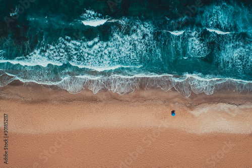 Aerial top view from drone of sandy beach with turquoise sea waves with copy space for text