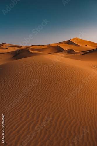 Vertical shot of a peaceful desert under the clear blue sky captured in Morocco
