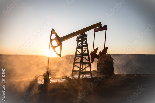 Creative artwork decoration. Oil pump and oil refining factory at sunset. Energy industrial concept. Selective focus.