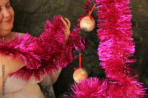 Fat woman decorates a Christmas tree. Joy of the upcoming holiday. Tree Decor