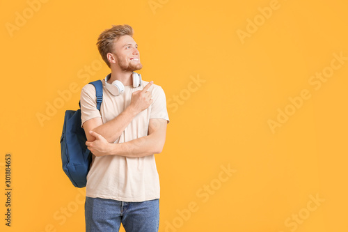 Portrait of male student showing something on color background