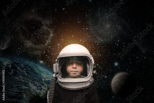 a small child imagines himself to be an astronaut in an astronaut's helmet.