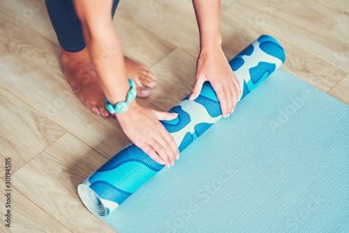 Young woman rolling yoga mat at home