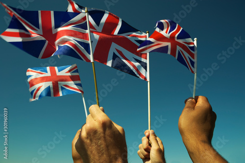 Group of patriotic hands waving Union Jack British flags in bright blue sky at a Brexit protest in London