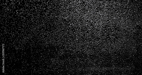 Drops of rain trickling down on black background.