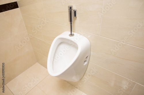 Modern stylish male urinal on the wall. Beautiful brown ceramic tile, copy space