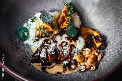 Haute cuisine - stew from beef, mushrooms and mashed potato in a bowl at dark background