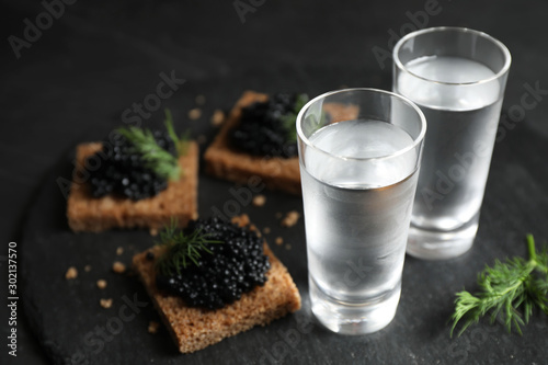 Cold Russian vodka and sandwiches with black caviar on table, closeup