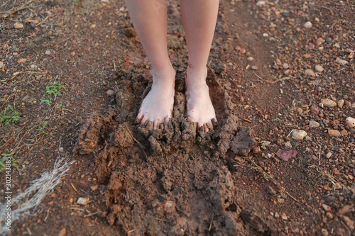 Kid bare foot with muddy feet on the rural road.