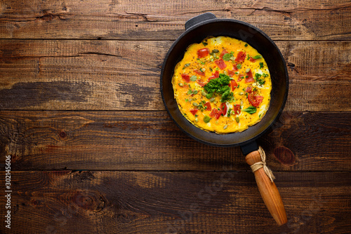 omelet with old cast iron pan on wooden background with copy space