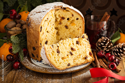 Traditional Christmas panettone with dried fruits and orange zest on rustic background