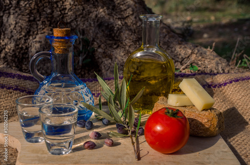 Cretan food with virgin olive oil, Olives,Cretan Barley Rusks, local cheese and carafe of cretan raki.