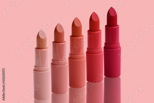 set of matte lipstick on a delicate pink background, red, raspberry, pink, coral, peach color, close-up, the concept of decorative cosmetics