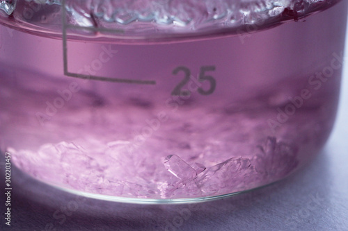 Manganese sulfate crystals grow in an aqueous solution in a beaker.