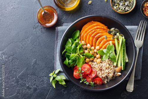 Healthy vegetarian salad. Roasted pumpkin, quinoa, tomatoes, green salad. Buddha bowl. Slate background. Top view.