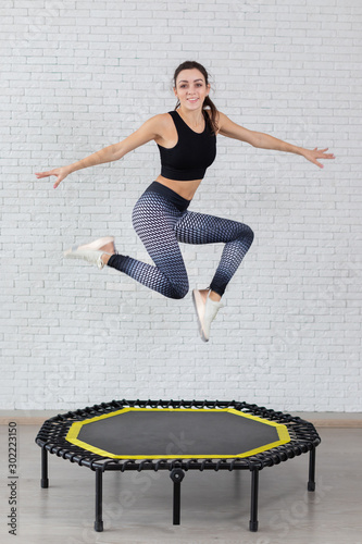 a young girl trains on a mini trampoline is engaged in fitness and stretching on a white background