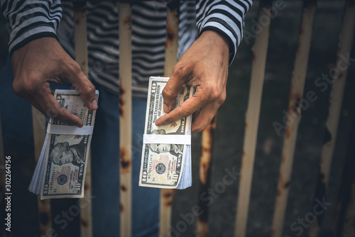 Male criminals Captured in a dirty cage On charges of counterfeiting a bank dollar, in which he held the fake banknote in his hand, to financial crime concept.