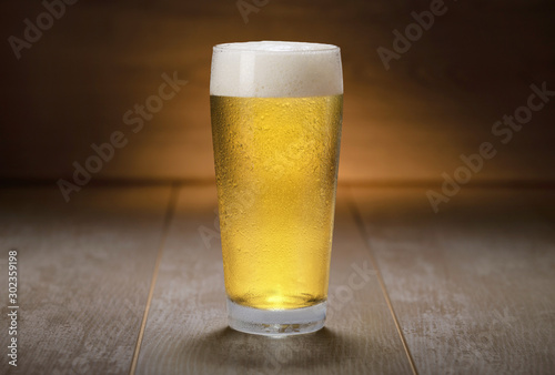 A colorful fresh pint glass of pale ale beer, pilsner, lager, traditional brew on wooden background