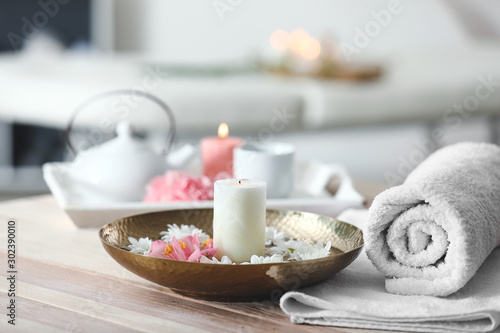 Towel, plate with flowers and candle on table in spa salon