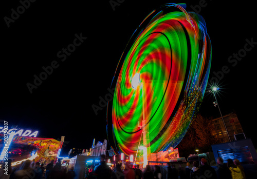 Ferris wheel in motion in the amusement park, at night. Long exposure photography.
