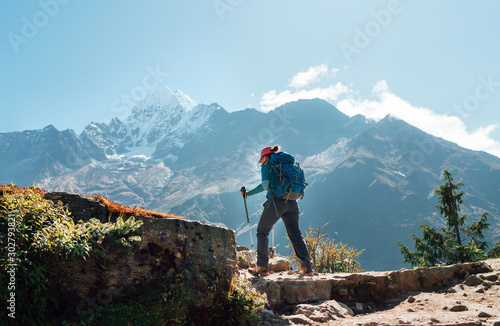 Young hiker backpacker woman using trekking poles enjoying Everest Base Camp trekking route with Thamserku 6608m mountain on background during high altitude Acclimatization walk in Sagarmatha NP,Nepal