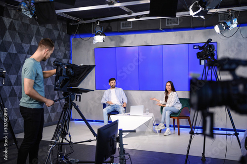 Presenters and video camera operator working in studio. News broadcasting