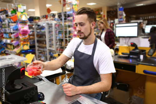 Male cashier checking out goods in supermarket