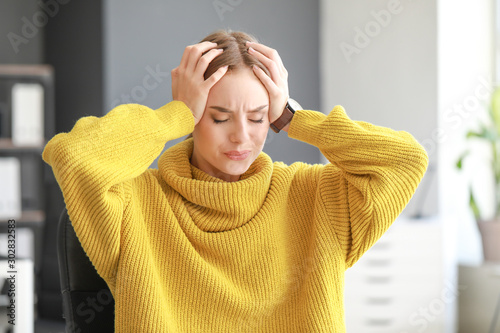 Young woman suffering from headache at home