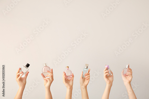 Female hands with different perfume bottles on grey background