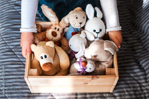 Little girl cleaning up the toy box at home. Child's space organization.