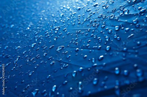 Water drops on waterproof nylon fabric. Macro detail view of texture of blue woven synthetic waterproof clothing. morning dew on camping tent close view. Rain