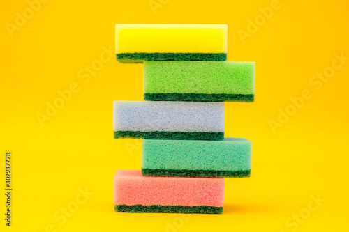 Multicolored sponges for cleaning folded pyramid on a yellow background. Space for text