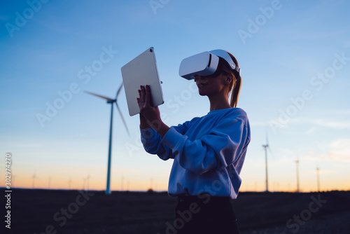 Female developer wearing VR goggles using touchpad during sundown