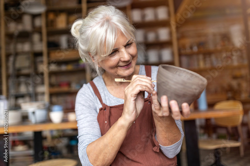 Senior woman pottery artist makes ceramics from clay