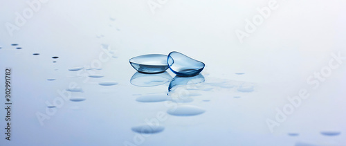 Contact lenses and water drops on light blue background. Eyewear, eyesight, eye care and health, ophthalmology and optometry