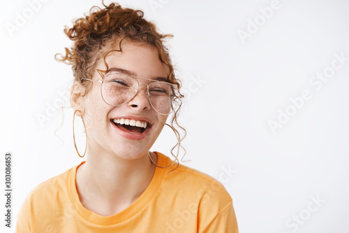 Carefree joyful happy young lucky redhead girl wearing glasses messy curly bun haircut laughing adore awesome funny humor jokes standing delighted white background grinning, white background
