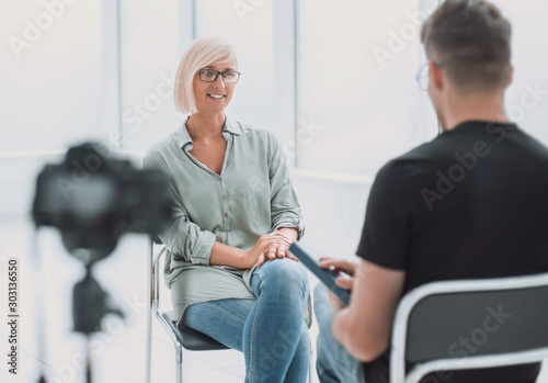 background image of a man and a woman sitting in the Studio during the interview
